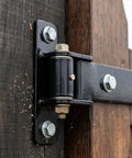 Rock Solid Stainless Steel T Shape Barn Door Hinge With Slick Bearing Heavy Duty Gate Hardware For Commercial And Garage Jobs Built To Last Rust Resistant Finish All Weather close-up view on wooden door with matte black finish and precision rollers.