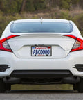 Rear view of white car with license plate secured by Black Anti Theft License Plate Screws Kit With Stainless Steel 1/4 Inch Security Mounting Hardware Includes Caps Inserts Rattle Proof Pads For Car Tags And Frame Mounting Easy Bolt On Tamper Proof Design