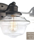 Close-up of 26 Inch 3 Light Traditional Schoolhouse Vanity Light with clear glass shade and gray finish for classic bath style.