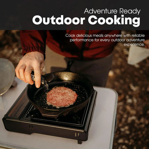 Person cooking meat on 10,000 BTU Dual Fuel Camp Stove For Butane And Propane Portable Outdoor Grill with cast iron pan