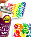 Spray Gloss Finish Acrylic Sealer 6 Oz Clear Coat For DIY Indoor And Outdoor Projects in use over colorful patterns