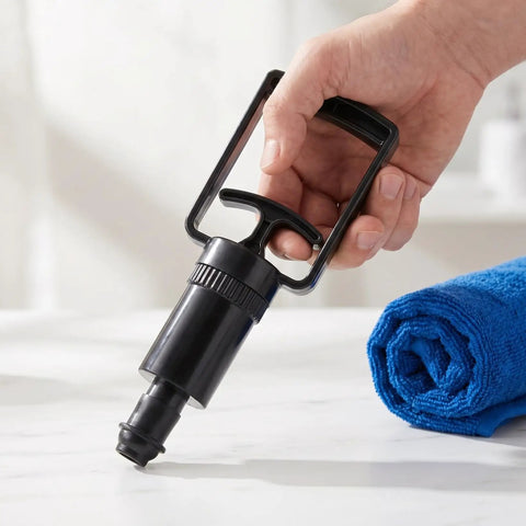 Hand holding Universal Replacement Manual Cupping Pump With Ergonomic Grip For Vacuum Cups beside a rolled blue towel.
