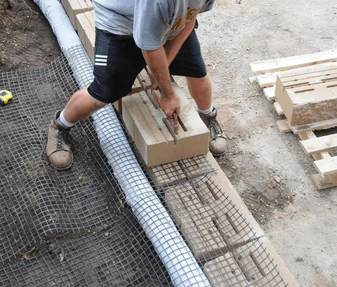 Man using Versa-Lok Versa Lifter Standard Tool for Easy And Safe Handling Of Block Walls while lifting concrete blocks.
