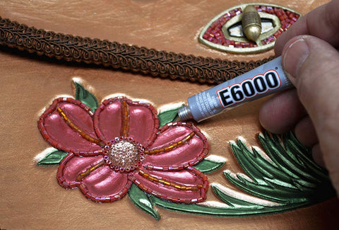 Craft Adhesive 4 Pack 0.18 Oz Tubes With Five Minute Open Time being applied to floral fabric embroidery.