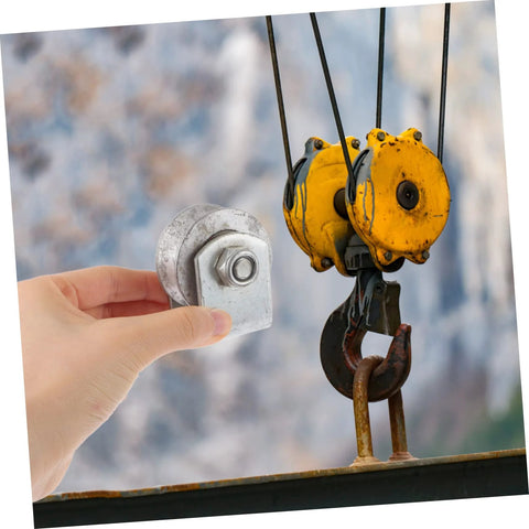 Heavy-duty cast-iron V-groove wheel held in hand; yellow double-pulley hoist assembly visible in background.