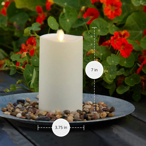 Outdoor Flameless LED Ivory Candle With Melted Edge, 3.75 x 7 Inches, Real Moving Flame on patio with flowers, Battery Powered.