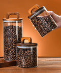 Premium Glass Coffee Canister With An Airtight Wooden Lid To Keep Your Daily Grind Fresh, storing coffee beans on a wooden counter.