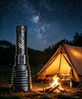 Ultra Bright 155,000 Lumen Rechargeable Flashlight With Zoomable Beam next to tent and campfire under starry sky
