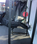 Person using Single Leg Squat Roller Attachment for Power Rack and Home Gym, Nordic Curls Kit, Bulgarian Split Squat Accessory