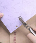 Dual Hole Punch Set With One Quarter Inch And One Eighth Inch Holes used on paper, ergonomic design shown in use