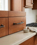 Oil Rubbed Bronze Cabinet Pulls with 5 Inch Hole Centers, 6 Pack displayed on a warm wood kitchen drawer