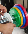 Loading a 0.5 Kg Barbell Change Plate With Grooved Inner Design onto bar, white finish, for stable lifts, home gym setting