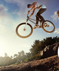 Cyclist airborne on cliff with pair of universal bike pedal toe straps, heavy duty replacement foot straps detail shown inset.