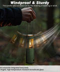 Person holding Compact Real Candle Lantern For Camping And Emergency Lighting in a windy forest, showing stability of the flame.