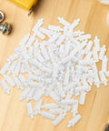 White Shutter Repair Pins, 120 Piece Movable Louver Fasteners scattered on wood surface, white plastic fasteners for shutters.