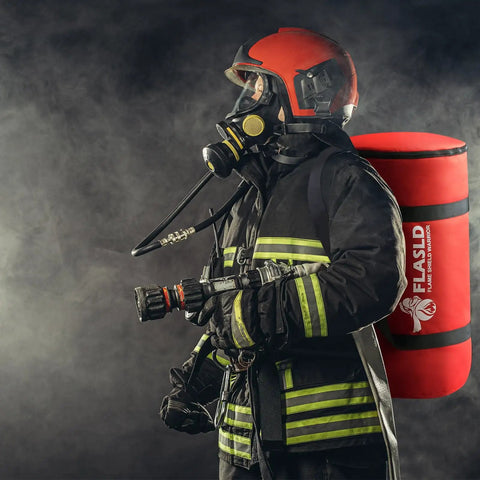 Firefighter wearing safety gear and holding equipment with fire suppression tools, standing against smoky background.
