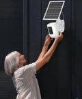 2 In 1 Solar Panel Wall Mount For Outdoor Security Camera With 7W Solar Charger on dark wall, woman adjusting camera