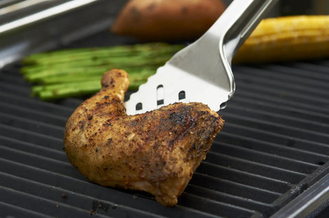 16-Inch Stainless Steel Tong And Turner Combo With Red Soft Grip Inserts holding grilled chicken on barbecue