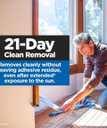Man using PROSharp Painter's Tape 1 in x 60 yd (0.94 in wide), 1 Roll Blue indoors for 21-day clean removal, showcasing application.