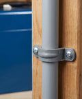 Thirty Pack Real Heavy Duty Three Quarter Inch Pvc Conduit Clamps mounted on a wooden post, securing a gray conduit pipe.