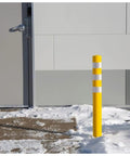 Real Deal Removable Safety Bollard 34.5 Inch Reflective Yellow Traffic Post in snow near building entrance.