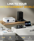 D1 Smart Projector With WiFi And Bluetooth Built In Apps Auto Focus And Keystone on shelf next to speakers and gaming console.