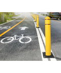 Heavy Duty Bollard Covers For Four Inch Outdoor Poles Fifty Six Inch Tall Post Sleeves protecting bike lanes with bright yellow poles on a road.