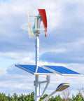 Vertical axis wind turbine with three colored blades atop a pole beside two solar panels; 12V 100W off-grid generator.