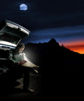 Man using Ultra Portable LED Pocket Flashlight With Twist On Off Tiny But Mighty 100 Lumens near car at night in mountain landscape