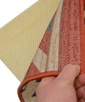 Hand lifting area rug to show Eco Friendly Non-Slip Rug Pad For Area Rugs And Runners With Extra Cushion Breathable Design underneath.