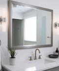 Modern 14 Inch Two Light Wall Sconce in Brushed Nickel Finish with Frosted Glass Cylinder Shades beside bathroom mirror