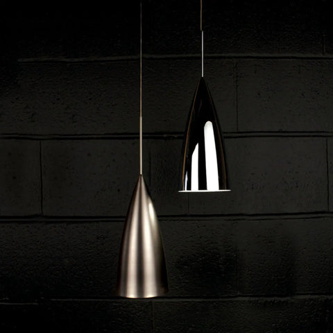 Two Dope Bullet LED Pendant Fixtures With Canopy In Chrome, sleek design, dimly lit against a dark brick wall backdrop.