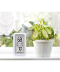 Digital Thermometer With Indoor And Outdoor Temperature Readout, Wireless sensor, beside a plant on a windowsill, showing readings.