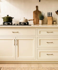 10 Pack Antique Brass Cabinet Pulls with Ergonomic Curved Grip for 5 Inch Kitchen Cabinets on cream drawers