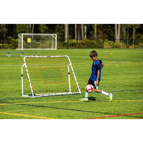 Child using Adjustable Soccer Rebounder 6 Foot By 4 Foot For Training with Angles on a field.