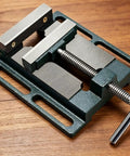 Beefy Bench Vise For Drill Press And Table Mounting Mini Vise With 360 Degree Handle And Rock Solid Clamping, Ideal For Workshop Projects, Metal Parts Holding, Filing And Milling, Easy Install With Elongated Slot Base And 101 Mm Hole Spacing. Cast iron bench vise with 65 mm jaws on wooden surface