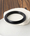 Male To Male M54x0.75 Telescope Adapter Ring For 50Mm Lens Filter resting on textured surface