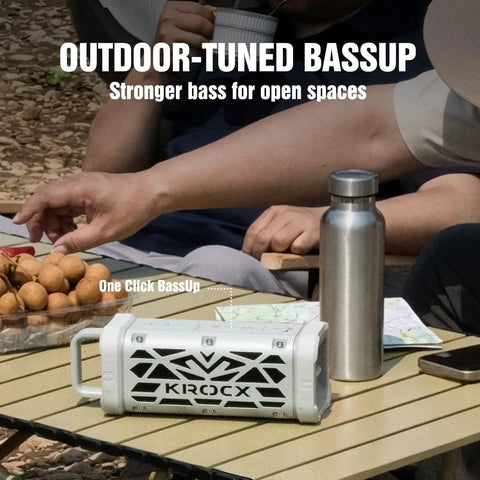 Rugged Aluminum Bluetooth Speaker With 45W Power Deep Bass IP68 Waterproof Magnetic Mounting TWS Pairing Long Battery Life Go To Outdoor Speaker For Golf Carts Camping And Beach Adventures In A Cloud Dancer Metallic Finish sits on a picnic table with water bottles and snacks.