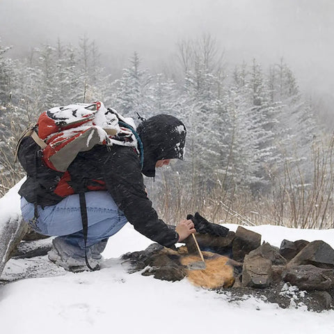 Person using Natural Jute Fire Starters 6-Piece Set For Quick Ignition in snowy forest to ignite campfire.