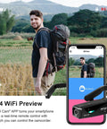 Man with backpack using Head Mounted 4K Video Camera for Hands Free Vlogging, app on phone shows live view, in a landscape setting.