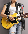 Black leather vest and matching wristband with silver pyramid studs, worn while playing a yellow guitar.