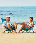 Two adults relaxing on a beach using Low Beach Chairs 2 Pack Folding Portable Chairs For Adults Ultra Wide Ergonomic High Back Seat 300 Lb Capacity Heavy Duty Outdoor Gear With Carry Bag For Lawn Camping Picnics.
