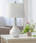 Ceramic Genie Tear Drop Table Lamp With Glossy Light Blue Base And White Fabric Shade placed on a table near flowers