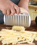 Rpanle stainless steel crinkle cutter with wooden handle slicing a potato into waves on a cutting board