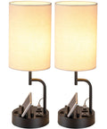 Bedside Table Lamp With Three USB Ports And AC Outlet Cream, Modern Desk Lamp With Built In Phone Stands, Dual Pack shown lit on black base.