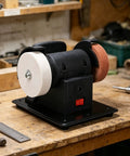Cordless mini bench grinder with coarse and fine grind wheels on workbench for quick metal polishing and sharpening tasks.