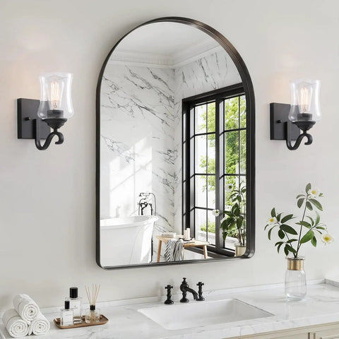 Winsmart Black Wall Sconces Set of Two Hard Wired with Clear Glass Shade beside a large arched mirror in a bathroom.