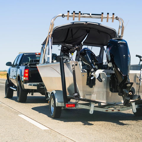 Truck towing boat secured with Beefy Retractable Transom Boat Tie Down Straps 2x43-Inch With 2500Lb Break Strength Auto Retract