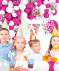 Children at party under Hot Pink And Silver Balloon Garland Arch Kit With Confetti Balloons For Weddings, Anniversary, Bachelorette Party, Birthday And Christmas Decor, Featuring Fuchsia Pink, Metallic Rose Red, White And Chrome Silver Balloons For A Party Ready Vibe.