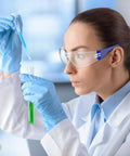 Woman wearing Heavy Duty Safety Glasses Bulk Pack With Clear Lenses And Durable Blue Frames, using a pipette in a lab.